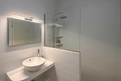 a white bathroom with a sink and a shower at Santamare Apartment in Agios Sostis