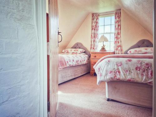 Schlafzimmer im Dachgeschoss mit 2 Betten und einem Fenster in der Unterkunft The Mansion Cottage in Tetford