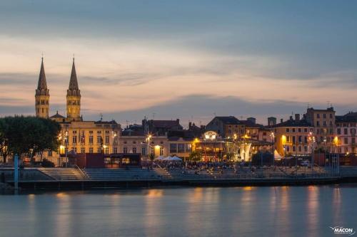 une ville de nuit avec une rivière et des bâtiments dans l'établissement Maison 6/8pers en Bourgogne, à Mâcon