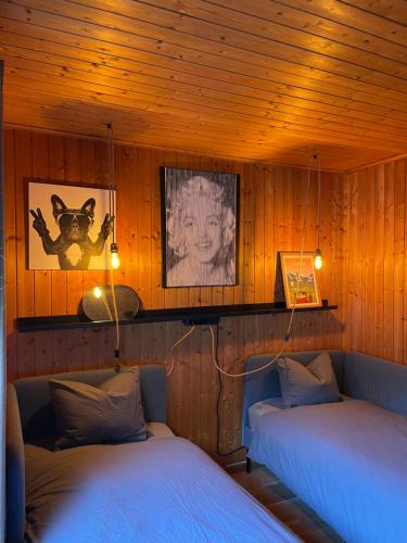 two beds in a room with wooden walls at Bel appartement près de Verbier in Bovernier