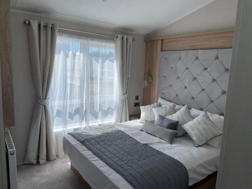 a bedroom with a large bed with a large window at Stunning Caravan With Full Sea Views At Broadland Sands In Suffolk Ref 20236bs in Hopton on Sea