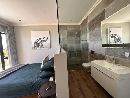 a bedroom with a bed and a bathroom with a sink at Luxury Home located on Pinnacle Point Golf Estate in Mossel Bay