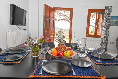 a dining table with a bowl of fruit on it at Santamare Apartment in Agios Sostis