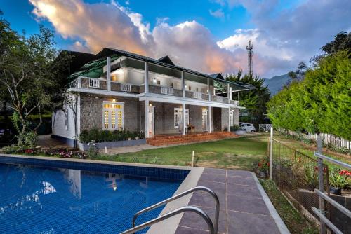 a house with a swimming pool in front of it at Nexstay Ministers Mansion in Kanthalloor