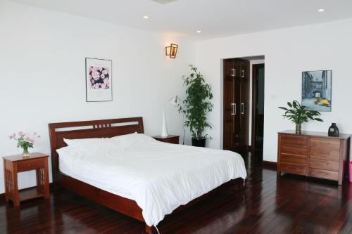 a bedroom with a bed with white sheets and wooden floors at Davidduc's apartment 23 Tay Ho in Hanoi