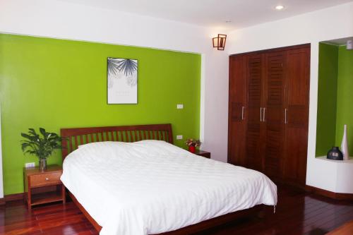 a green bedroom with a white bed and a green wall at Davidduc's apartment 23 Tay Ho in Hanoi