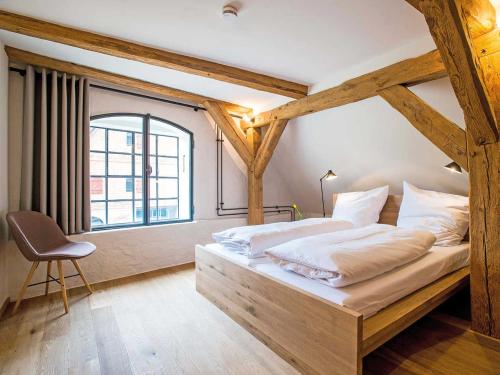 a bedroom with a bed with a wooden frame and a window at Kultur Gut Hasselburg in Altenkrempe