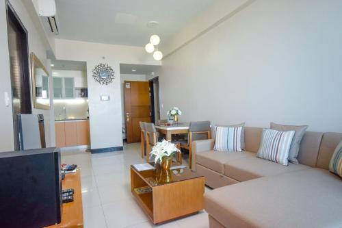 a living room with a couch and a table with a tv at Mactan Newtown Condo in Mactan