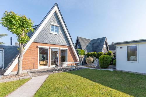 a house with a table and chairs in a yard at Ferienhäuser in Duhnen - Ringwall Seegras in Cuxhaven