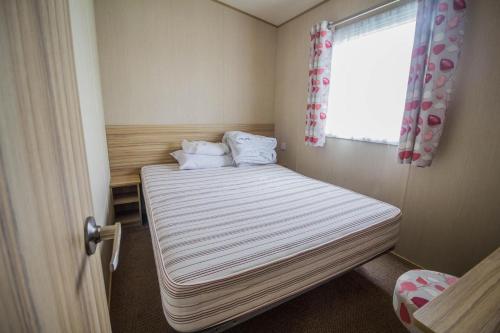 a small room with a bed and a window at Great 8 Berth Caravan In Norfolk Near To Great Yarmouth Ref 20178bs in Hopton on Sea