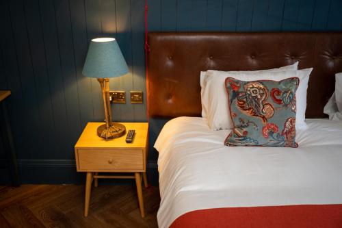 a bed with a nightstand with a lamp and a pillow at Victoria Hotel by Chef & Brewer Collection in Menai Bridge