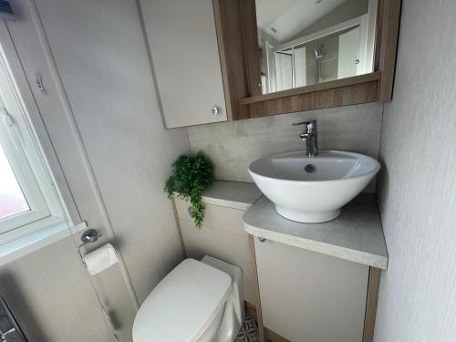 ein kleines Bad mit einem Waschbecken und einem WC in der Unterkunft Beautiful Lodge With Full Sea Views At Broadland Sands In Suffolk Ref 20235bs in Hopton on Sea