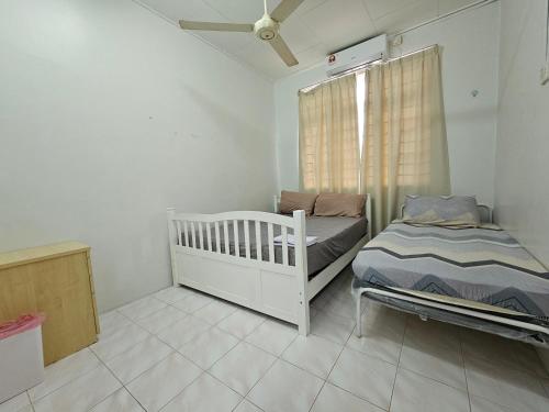 um pequeno quarto com um berço e uma cama em Ruhani Homestay 3 KB - 4 Bedroom Fully Airconditioned with WIFI & Netflix em Kota Bharu