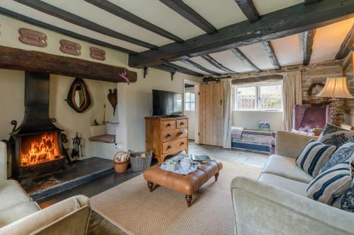 a living room with a couch and a fireplace at Rose Cottage in Evesham