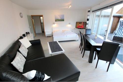 ein Wohnzimmer mit einem schwarzen Sofa und einem Tisch in der Unterkunft Kugelbake in Cuxhaven