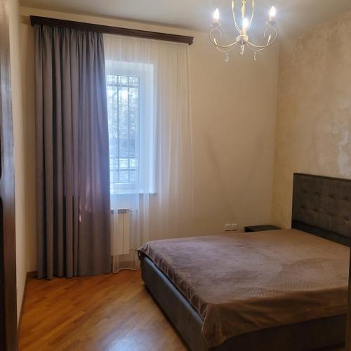 a bedroom with a bed and a window with a chandelier at Family home in Yerevan