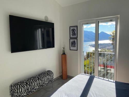 a bedroom with a bed and a tv and a window at Casa Collina in Locarno