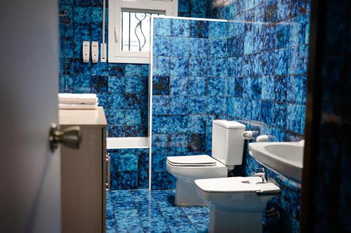 Baño de azulejos azules con aseo y lavamanos en Mirador del Llac, en Cellers