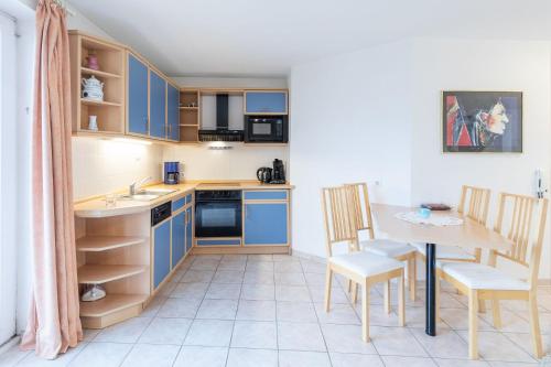 een keuken met blauwe kasten en een tafel en stoelen bij Wohnung 2 in Cuxhaven