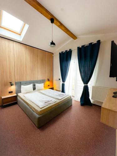 a bedroom with a large bed and blue curtains at Vila M 36 in Topliţa