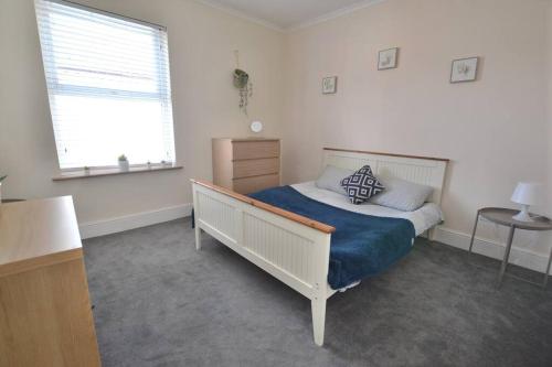 a bedroom with a bed with a blue blanket and a window at Church View in Quorndon