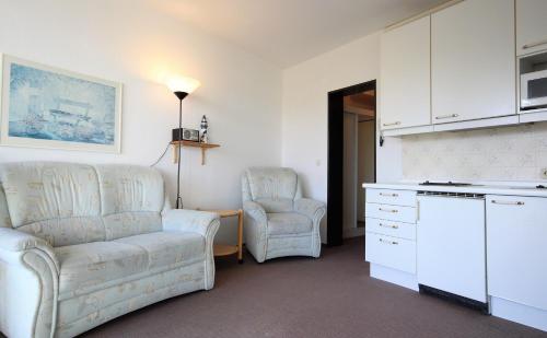 een woonkamer met 2 stoelen en een bank bij Haus Seehuette Wohnung 402 in Cuxhaven