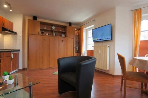 ein Wohnzimmer mit einem schwarzen Stuhl und einem TV in der Unterkunft Haus Elbe 1 Wohnung 18 in Cuxhaven