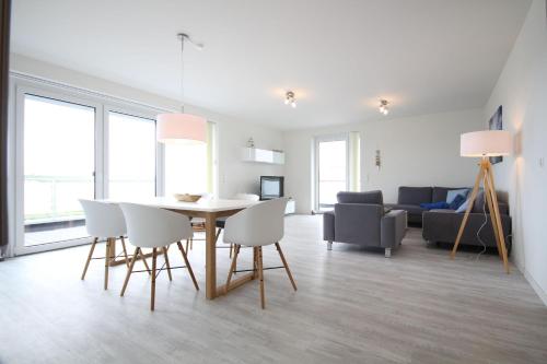 a dining room and living room with a table and chairs at Quartier Hohe Geest _ Wohnung Meer in Cuxhaven