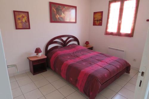 a bedroom with a bed with a red comforter at Un petit coin de paradis en bord de mer in Vias
