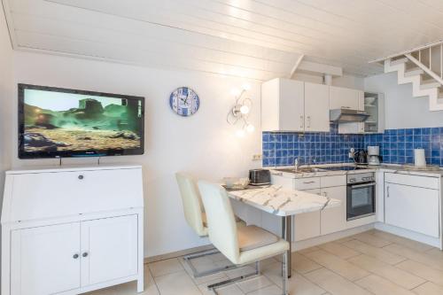 uma cozinha com uma mesa e uma televisão na parede em Haus Seewind Wohnung 2 em Cuxhaven