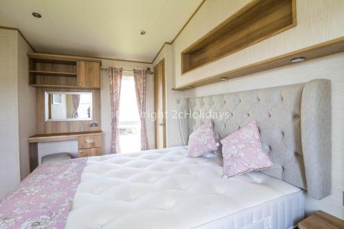 um quarto com uma grande cama branca com almofadas cor-de-rosa em Brilliant Caravan For Hire At Caister Haven Holiday Park In Norfolk Ref 30011h em Great Yarmouth
