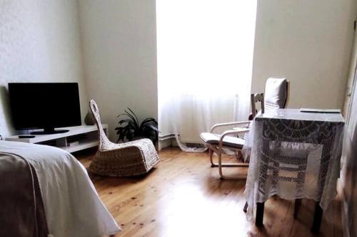 a living room with a tv and chairs and a bed at Autrefois la Cure in Bonnefontaine