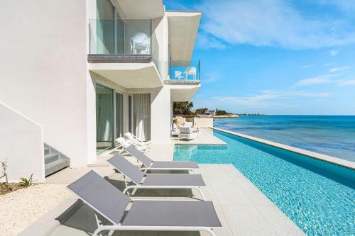 a swimming pool with chaise lounge chairs next to the ocean at Bedda Matri in Noto
