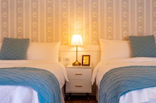 a bedroom with two beds and a lamp on a night stand at Flower Happiness Homestay in Jian