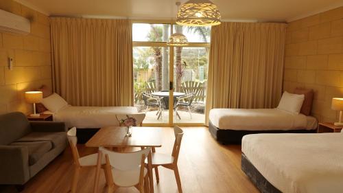 Cette chambre comprend deux lits, un canapé et une table. dans l'établissement Portside Motel, à Port Campbell