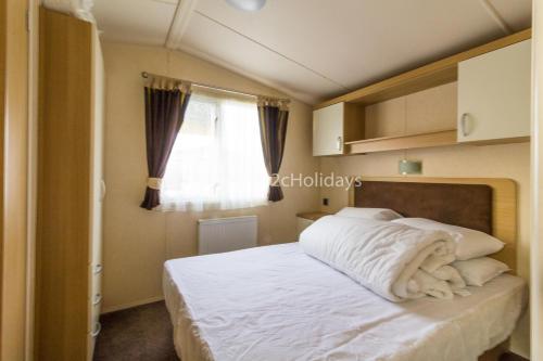 - une chambre avec un lit doté de draps blancs et une fenêtre dans l'établissement 8 Berth, Dog Friendly Caravan At Haven Caister In Norfolk Ref 30031b, à Great Yarmouth