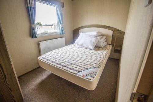 a small bed in a small room with a window at Superb 8 Berth Caravan At Caister Beach In Norfolk Ref 30073f in Great Yarmouth