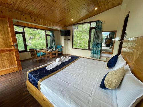 a bedroom with a large bed in a room with windows at The Royal Majestic Mountain View in Manāli