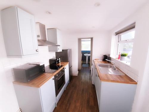 a kitchen with white cabinets and a sink at May Disc - Long Stay - Contractors in Swindon
