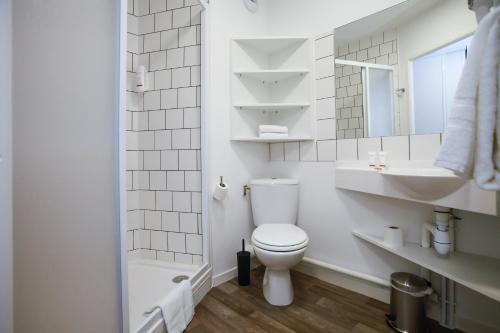 a white bathroom with a toilet and a sink at Odalys City Paris Levallois in Levallois-Perret