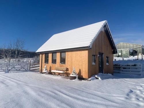 a wooden building with a snow covered roof at Cruachan Cabin in Skeabost