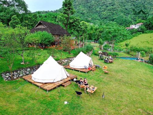 a group of people sitting in chairs in a field with tents at Đào Hoa Glamping in Hanoi