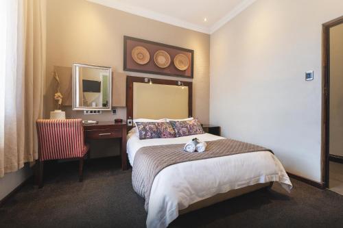 a hotel room with a bed and a desk and a mirror at The Graham Hotel in Grahamstown