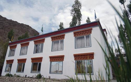 Norbooling HomeStay, Leh Ladakh في ليه: مبنى أبيض مع العديد من النوافذ على تلة