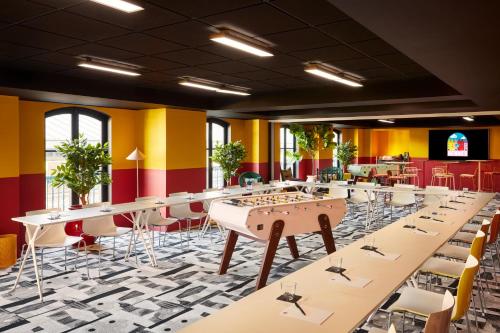 a large room with tables and chairs and yellow walls at Mama Shelter Rennes in Rennes