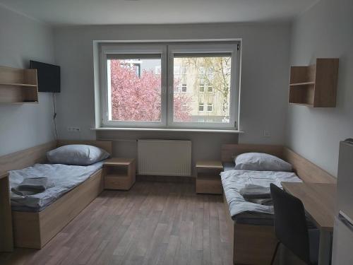 a room with two beds and a window at Dom Studencki Komenik in Leszno