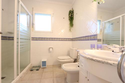 Baño blanco con aseo y lavamanos en Villa Xoriguer, en Denia