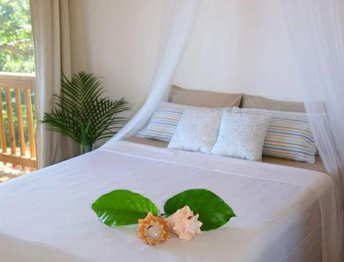 a white bed with two green leaves on it at apartmán Roatan A24 Czech Village in Arrozal