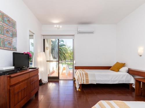 um quarto com uma cama, uma televisão e uma varanda em Akisol Cabanas Tavira Jungle em Cabanas de Tavira