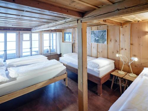 two beds in a room with wooden walls at Gästehaus Hof Maiezyt in Habkern